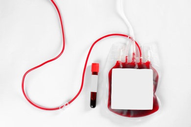 Photo of Blood pack for transfusion and test tube on white background, top view. Donation day