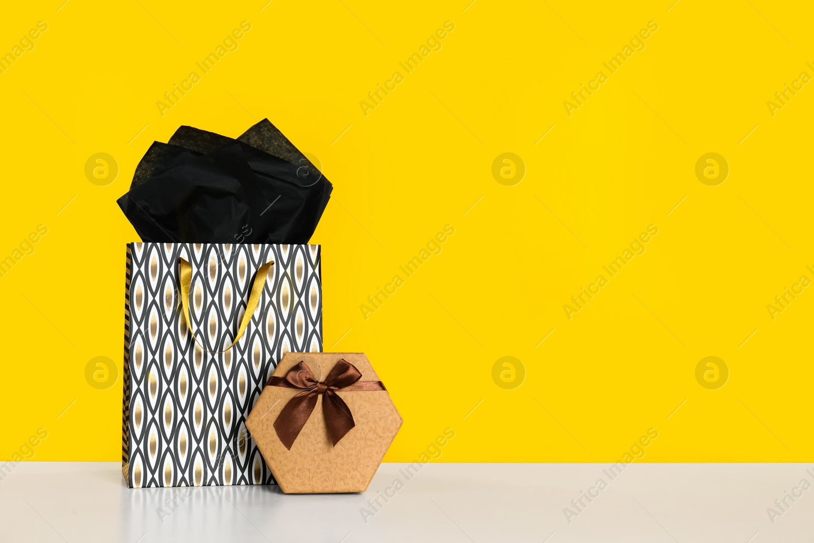 Photo of Shopping bag and gift box on yellow background. Space for text