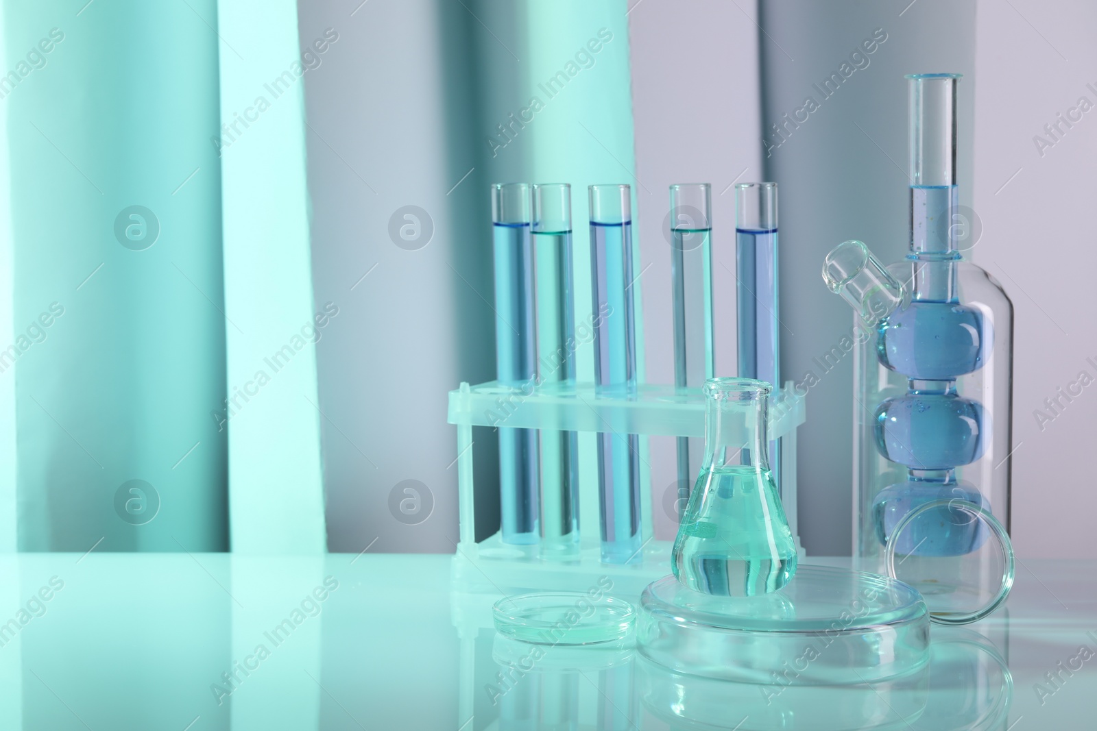 Photo of Laboratory analysis. Different glassware on table against color background, space for text