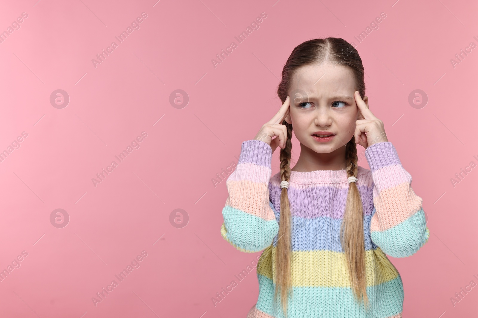 Photo of Little girl suffering from headache on pink background. Space for text