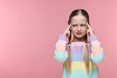 Little girl suffering from headache on pink background. Space for text