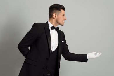 Photo of Handsome butler in elegant uniform on grey background