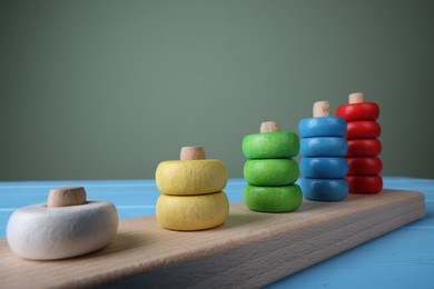 Photo of Stacking and counting game pieces on light blue table against grey wall, closeup. Motor skills development