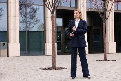 Photo of Female real estate agent with leather portfolio outdoors