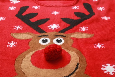 Warm red Christmas sweater with deer as background, closeup view