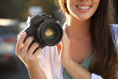Young photographer with professional camera outdoors, closeup