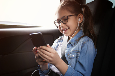 Cute little girl listening to audiobook in car