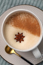 Cup of delicious eggnog with anise on wooden table, top view