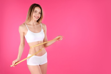 Photo of Slim woman measuring her waist on color background, space for text. Perfect body