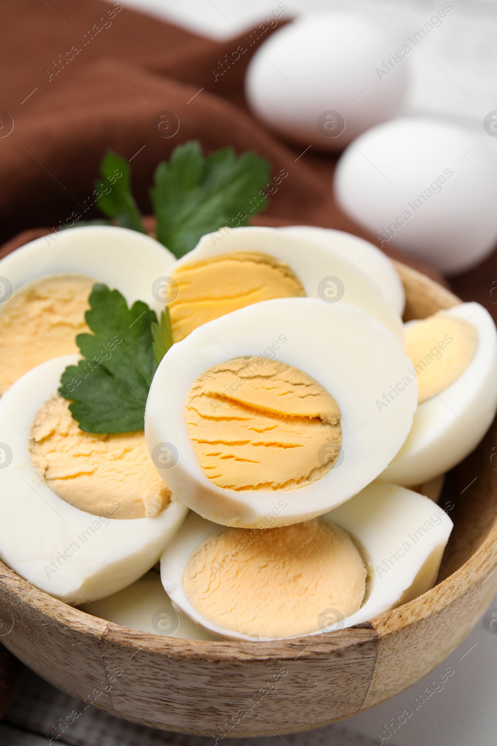 Photo of Wooden bowl with fresh hard boiled eggs and parsley on table, closeup