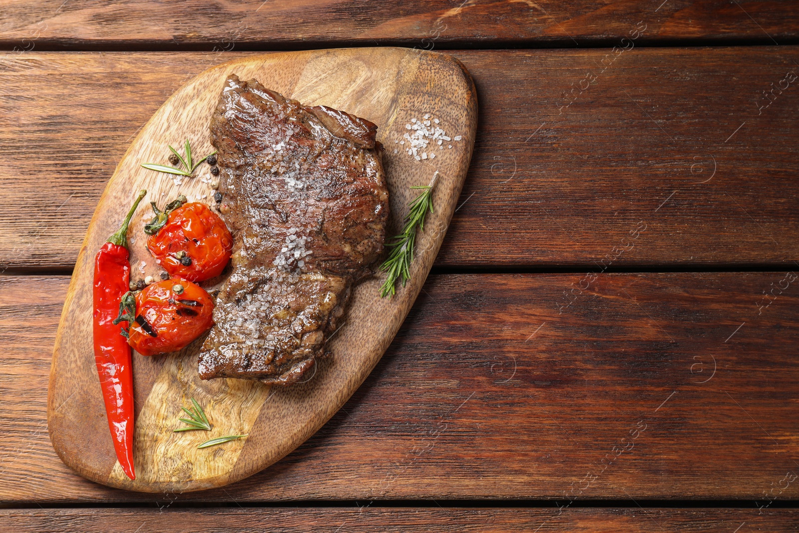 Photo of Delicious roasted beef meat, vegetables and spices on wooden table, top view. Space for text