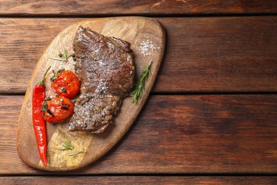 Delicious roasted beef meat, vegetables and spices on wooden table, top view. Space for text