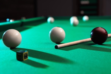 Billiard balls, cue and chalk on table indoors