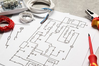 Photo of Wiring diagrams, wires and tools on grey table, closeup