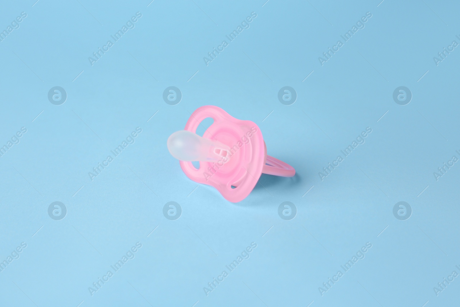 Photo of One new baby pacifier on light blue background