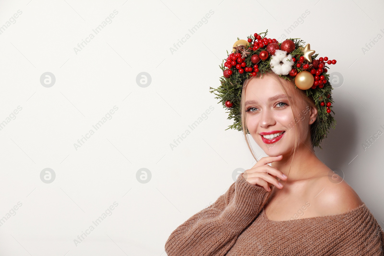 Photo of Beautiful young woman wearing Christmas wreath on white background. Space for text