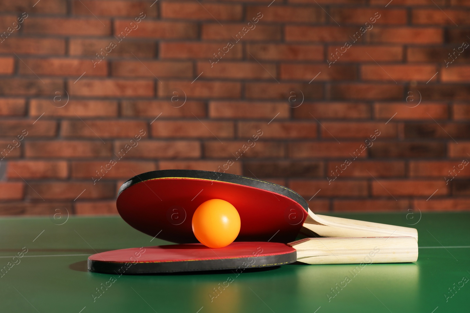 Photo of Rackets and ball on ping pong table indoors, space for text