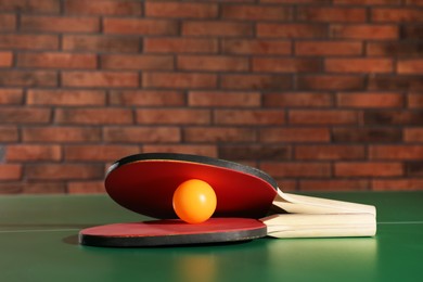 Photo of Rackets and ball on ping pong table indoors, space for text