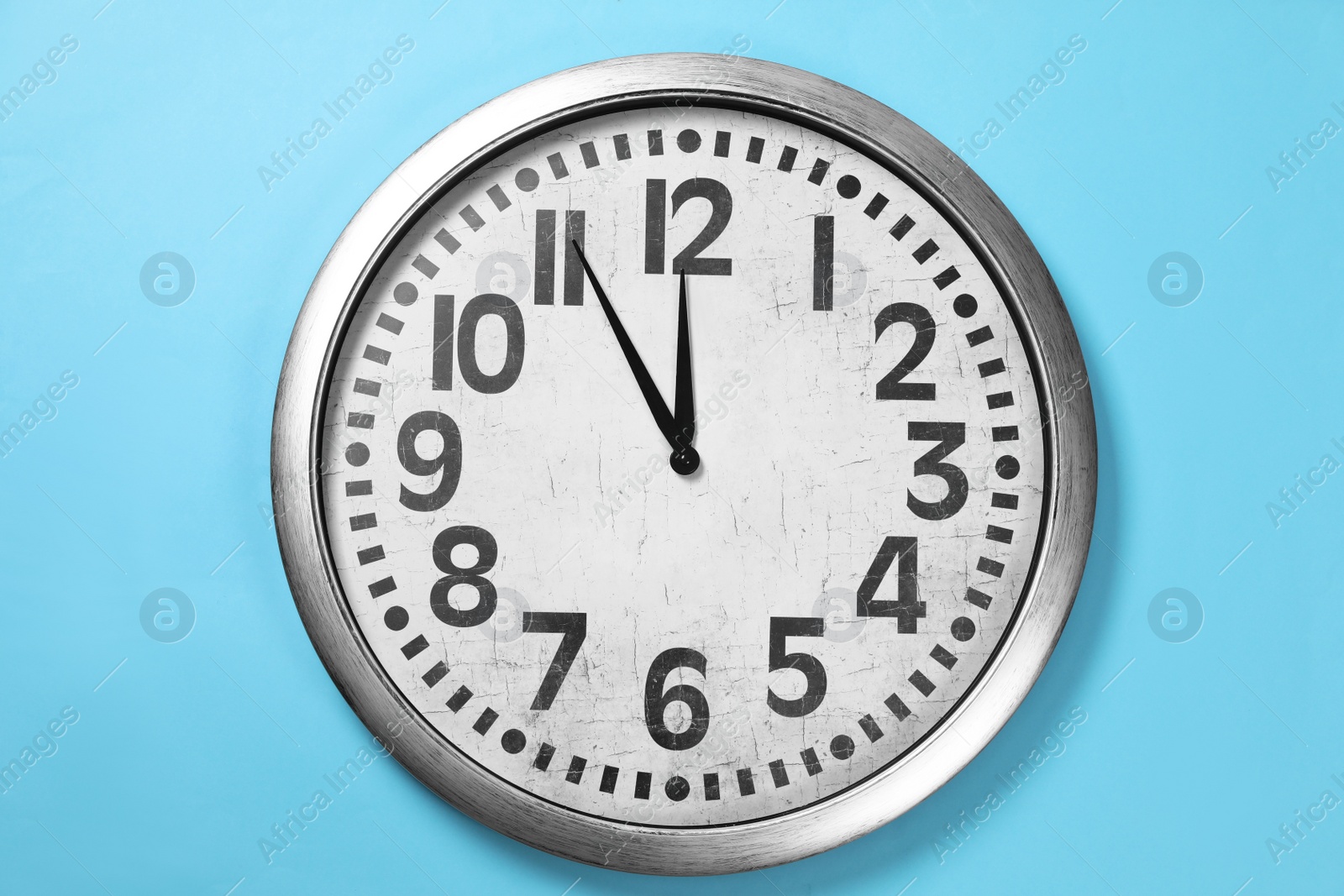 Photo of Stylish analog clock hanging on light blue wall. New Year countdown