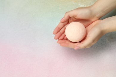 Woman holding bath bomb over water with foam, top view. Space for text