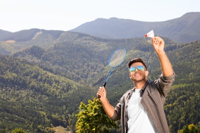 Man playing badminton in mountains on sunny day. Space for text