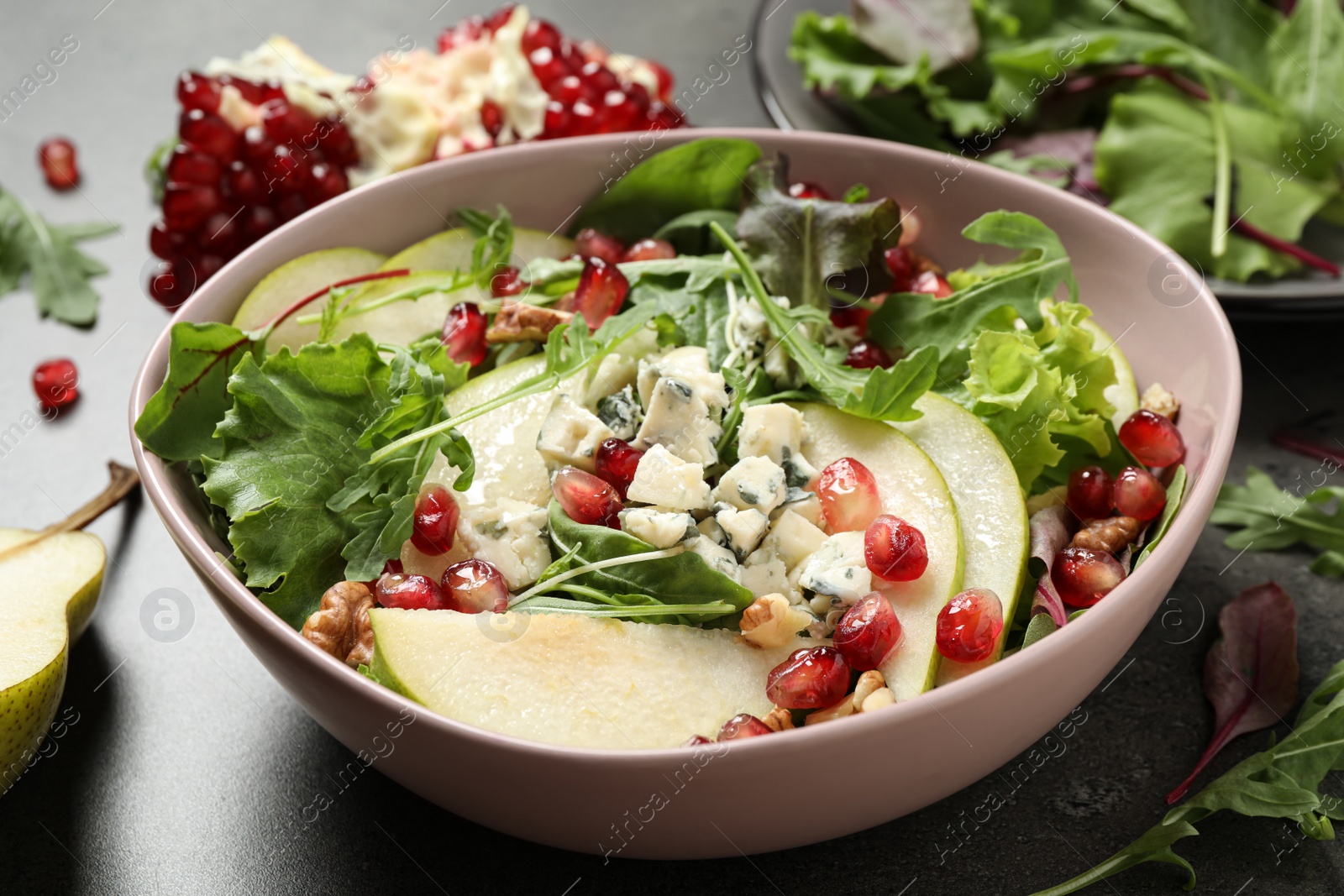 Photo of Tasty salad with pear slices and pomegranate seeds on table, closeup