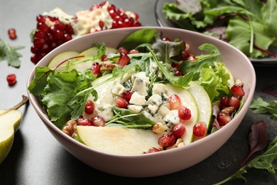 Photo of Tasty salad with pear slices and pomegranate seeds on table, closeup