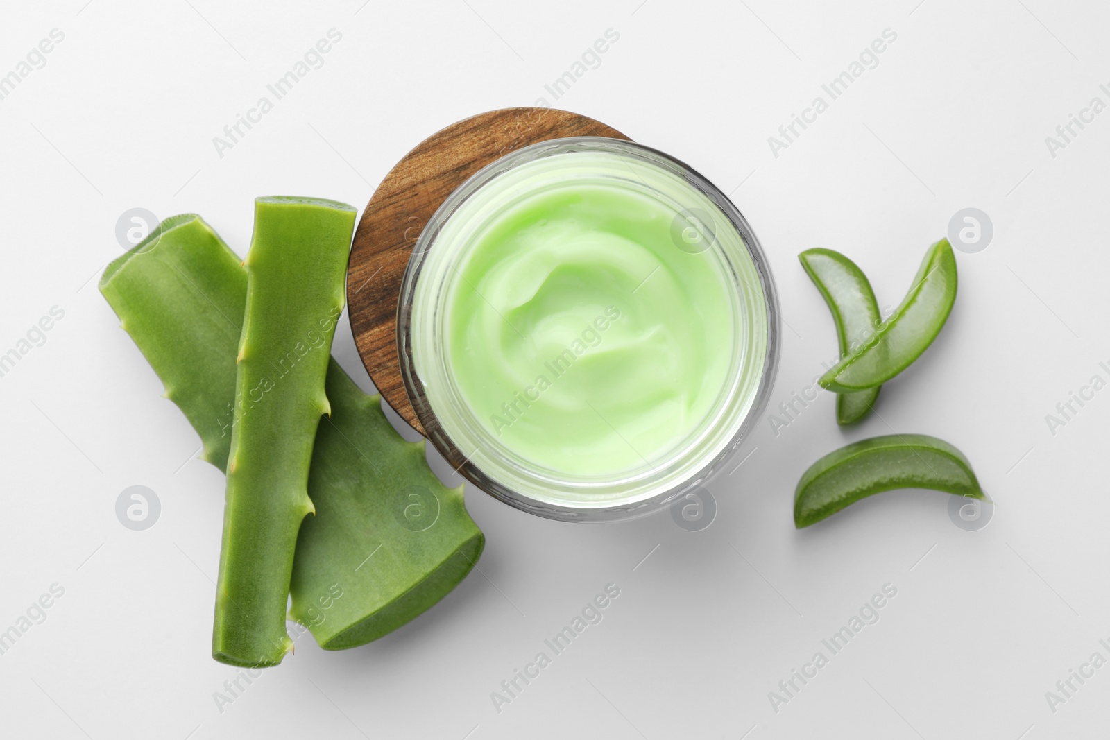 Photo of Jar of cosmetic cream and cut aloe leaves on white background, flat lay