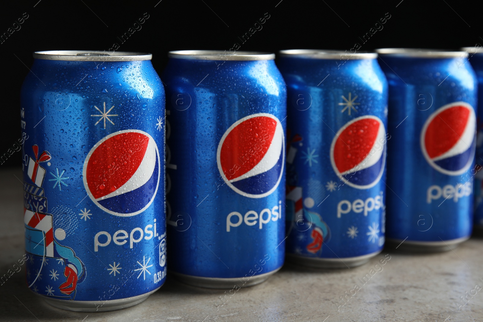 Photo of MYKOLAIV, UKRAINE - FEBRUARY 9, 2021: Many cans of Pepsi on table against black background