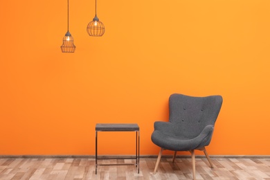 Comfortable armchair and small table against color wall