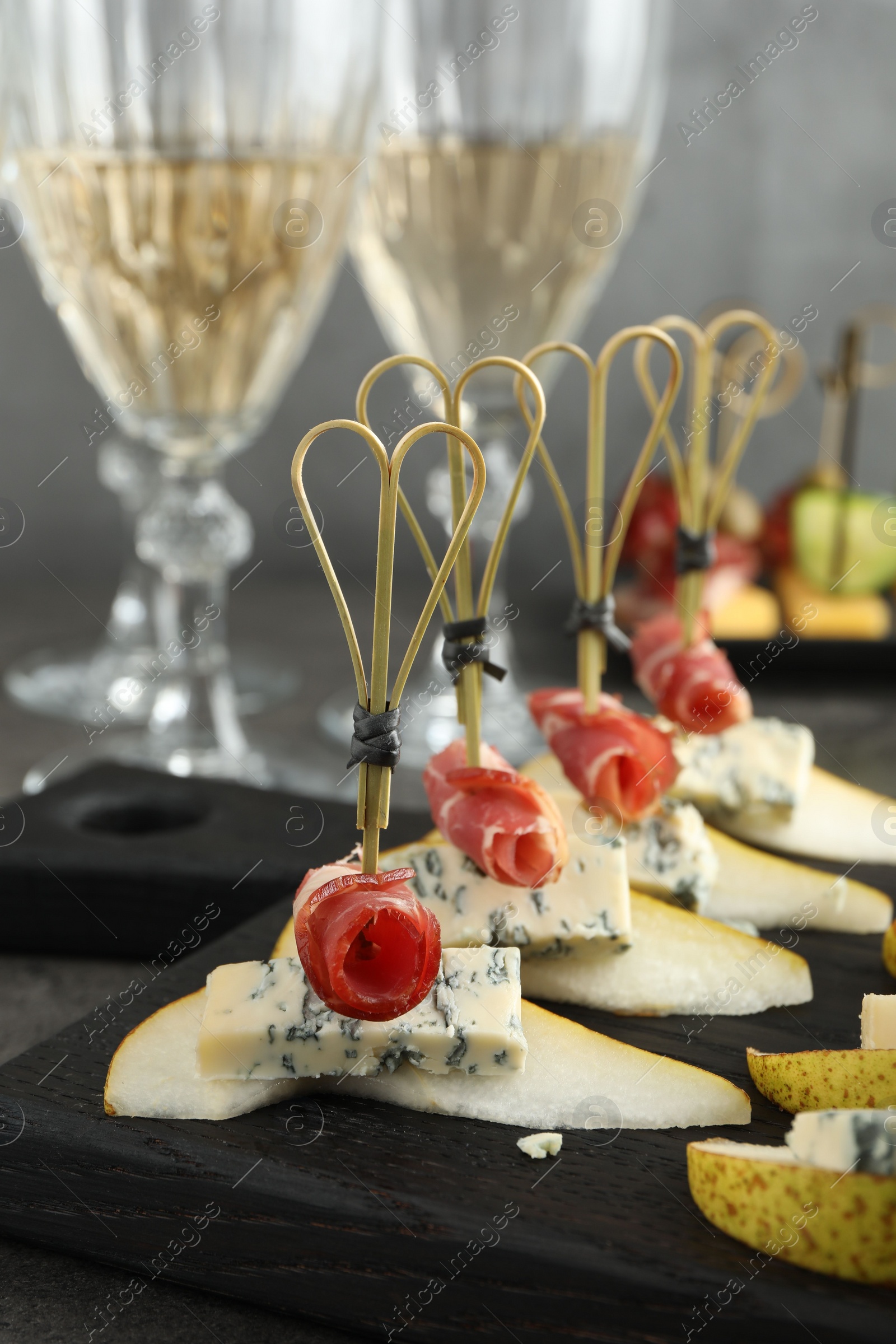 Photo of Tasty canapes with pears, blue cheese and prosciutto on table, closeup