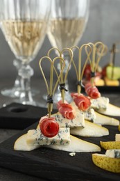 Photo of Tasty canapes with pears, blue cheese and prosciutto on table, closeup