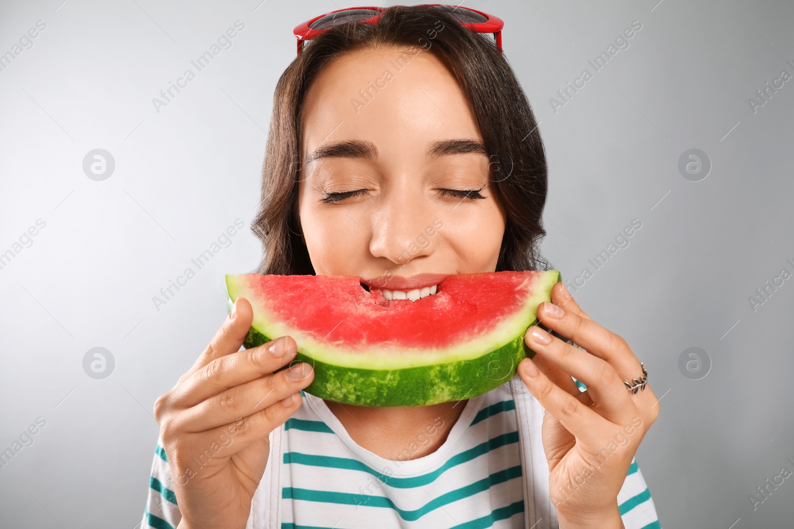 Photo of Beautiful young woman eating watermelon on grey background