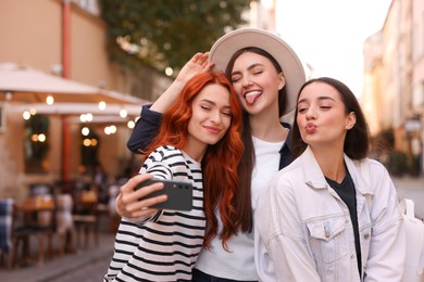 Happy friends taking selfie on city street