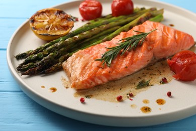 Tasty grilled salmon with tomatoes, asparagus and spices on table, closeup