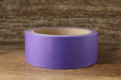 Photo of Roll of violet adhesive tape on wooden table