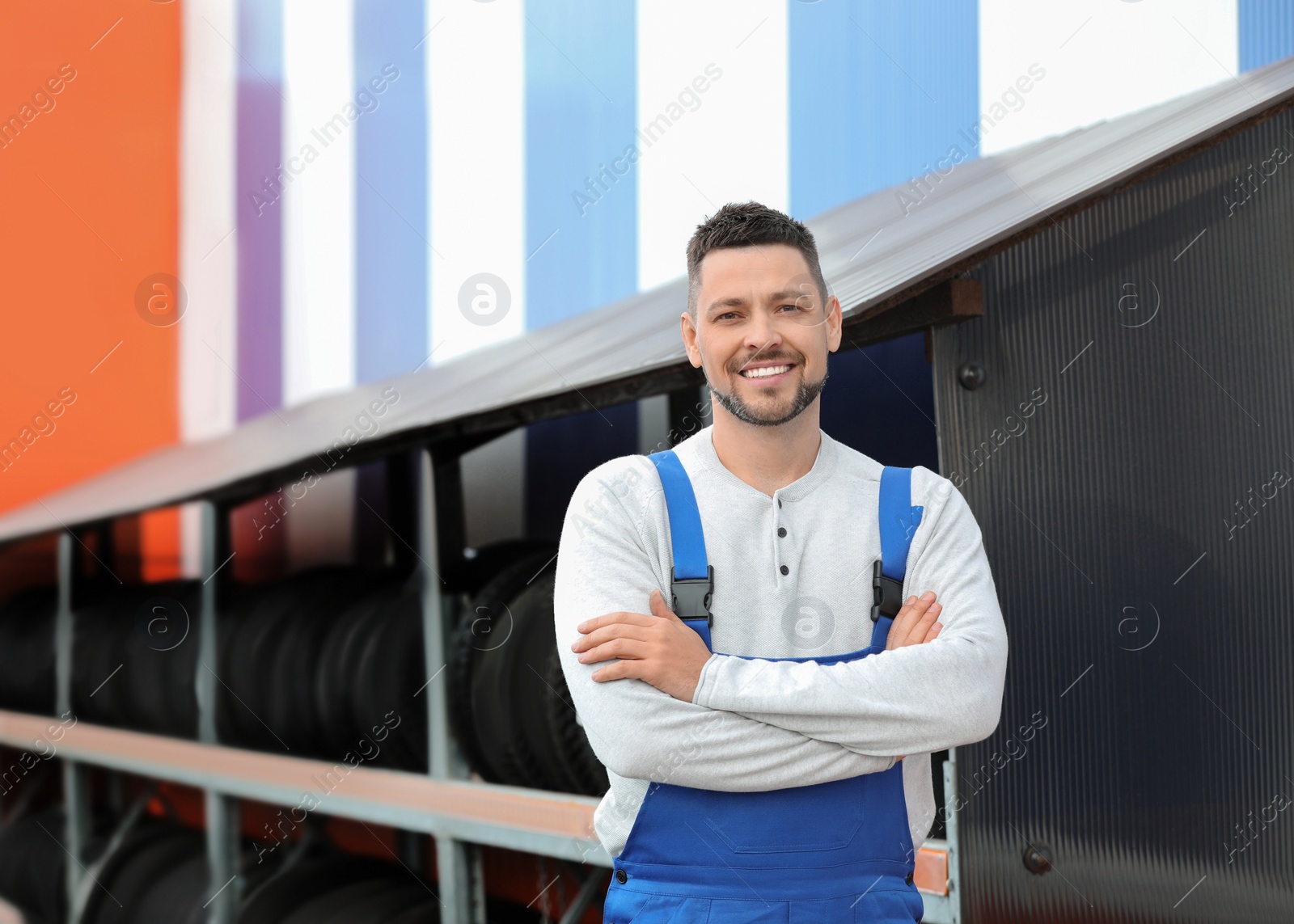 Photo of Mechanic near rack with car tires at service station. Space for text