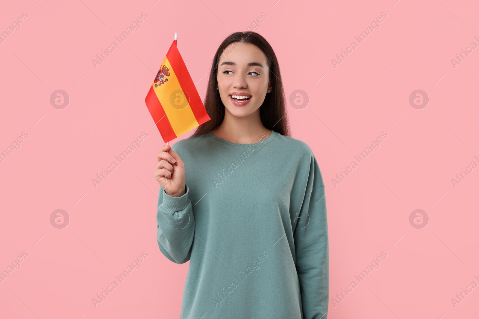 Photo of Young woman holding flag of Spain on pink background