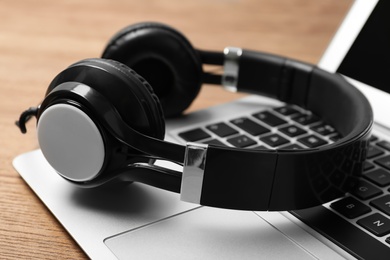 Photo of Modern headphones and laptop on table, closeup