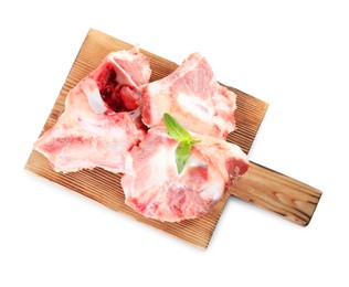 Photo of Wooden board with raw meaty bones and basil on white background, top view