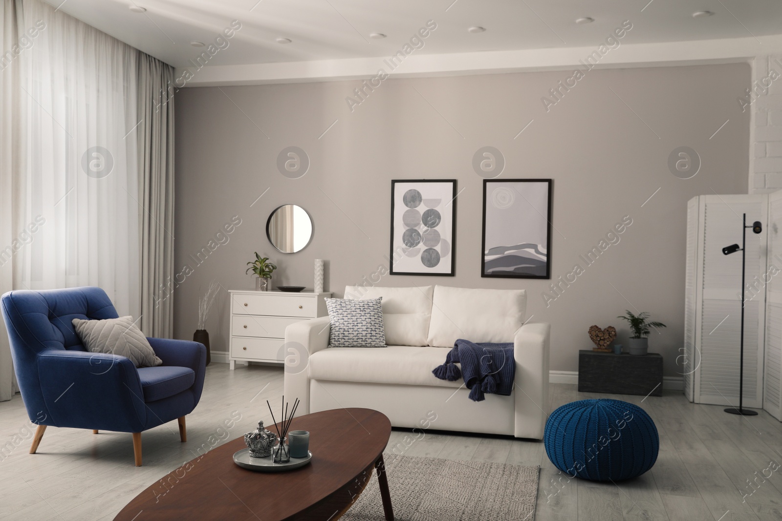 Photo of Stylish living room interior with white sofa, armchair and beautiful pictures