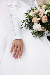 Bride wearing engagement ring and wedding dress with beautiful bouquet, closeup