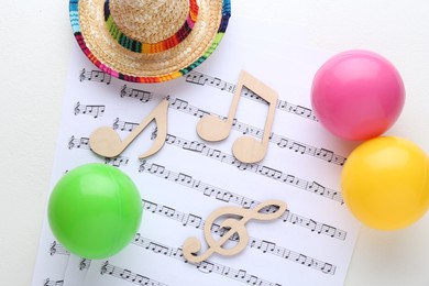Photo of Wooden notes, music sheets, hat and toy balls on white background, flat lay. Baby song concept