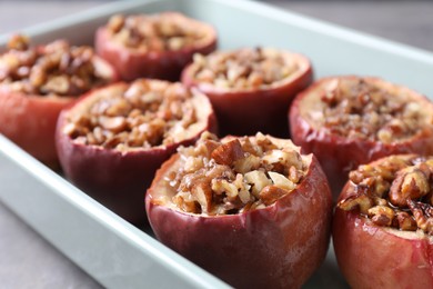 Tasty baked apples with nuts and honey in dish on table, closeup