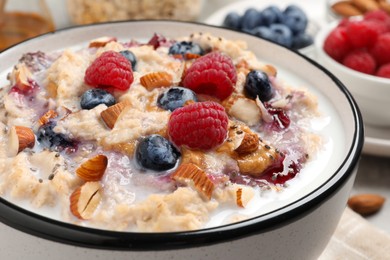 Photo of Tasty oatmeal porridge with toppings on table, closeup