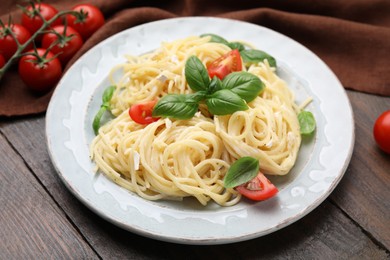 Photo of Delicious pasta with brie cheese, tomatoes and basil leaves on wooden table, closeup