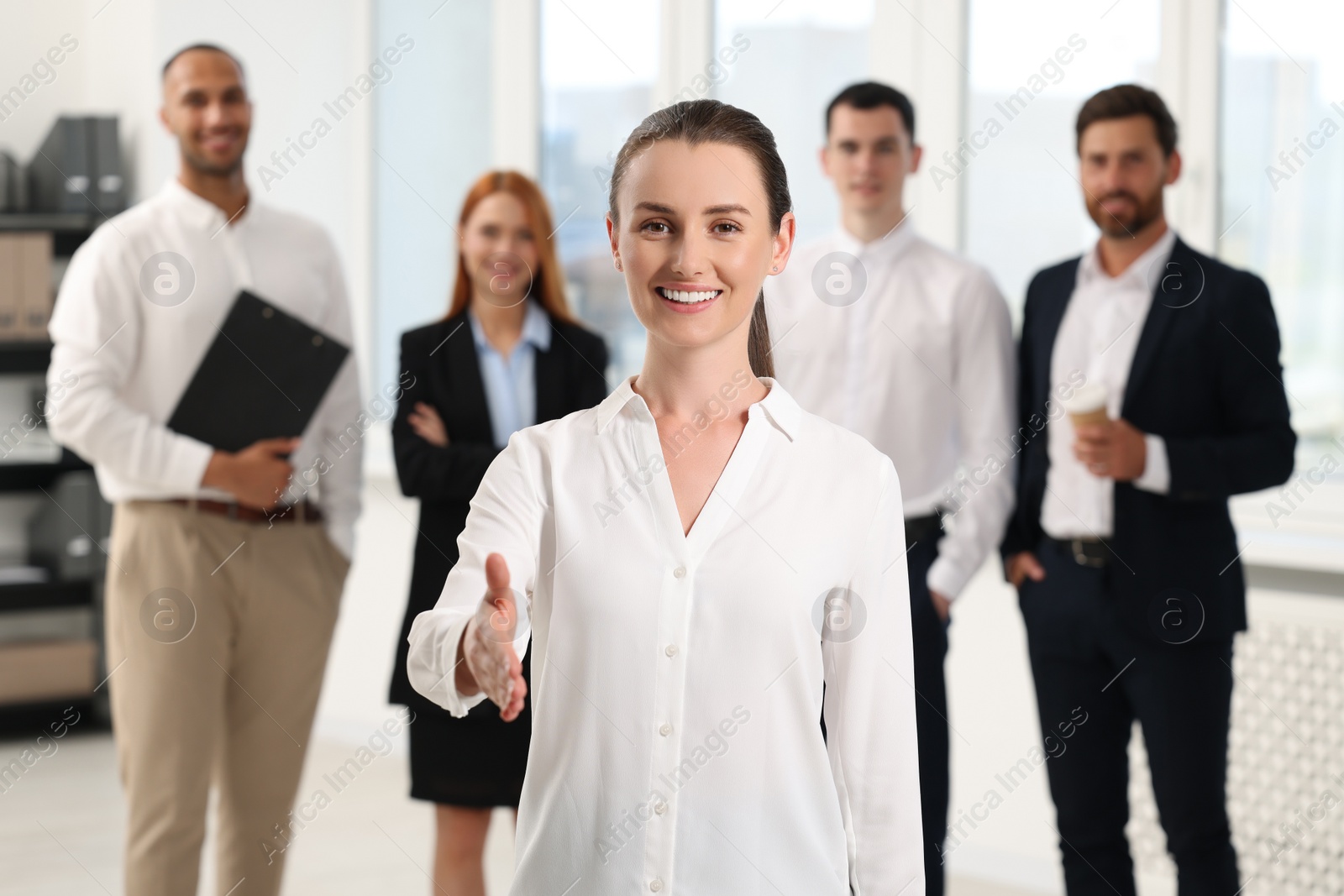 Photo of Group of people in office. Happy woman welcoming and offering handshake indoors