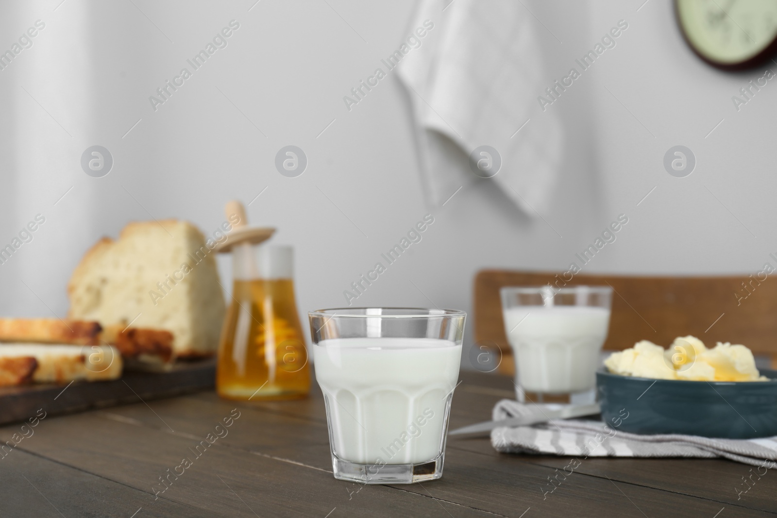 Photo of Delicious milk, honey, butter and bread served for breakfast on wooden table