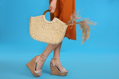 Photo of Young woman with stylish knitted bag on light blue background, closeup