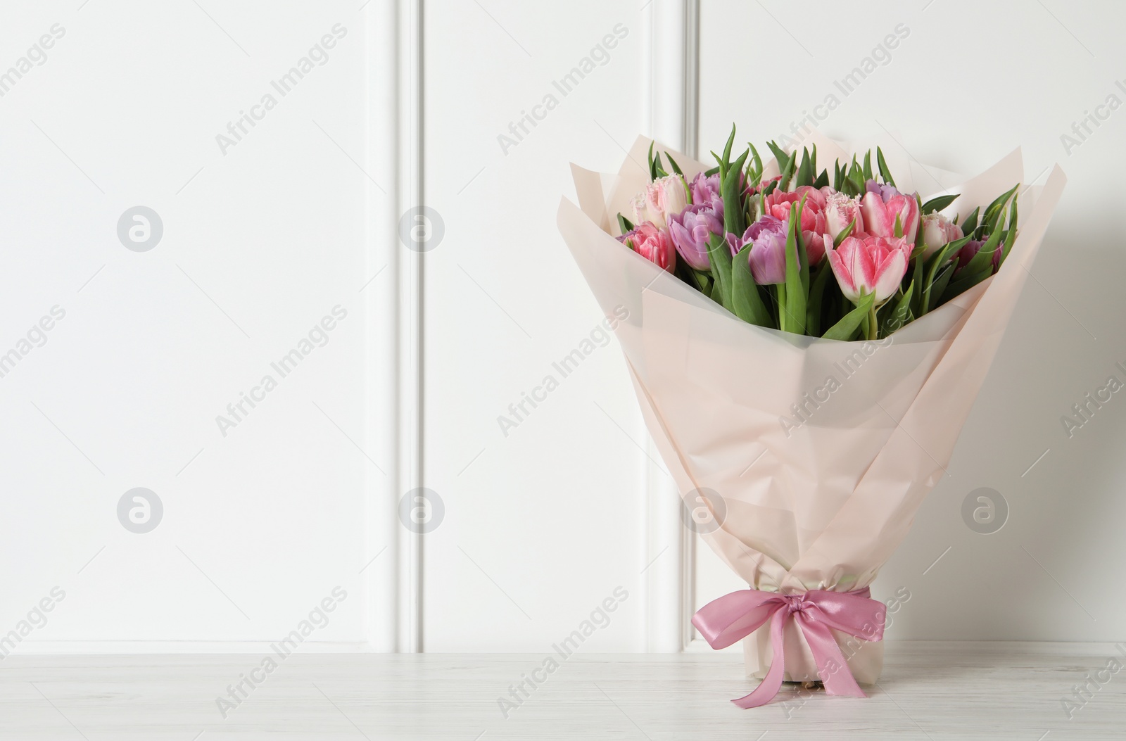 Photo of Bouquet of beautiful tulips on white wooden table. Space for text